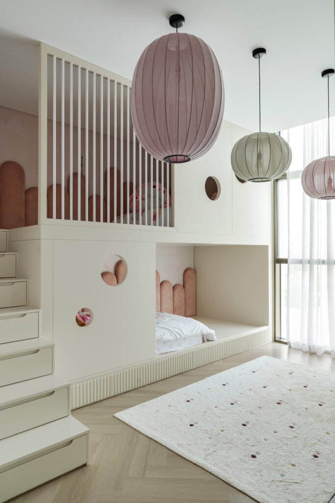 The bunk arrangement treated as architecture, with scalloped velvet headboards, porthole cutouts and lantern pendants in mauve, sage and rose
