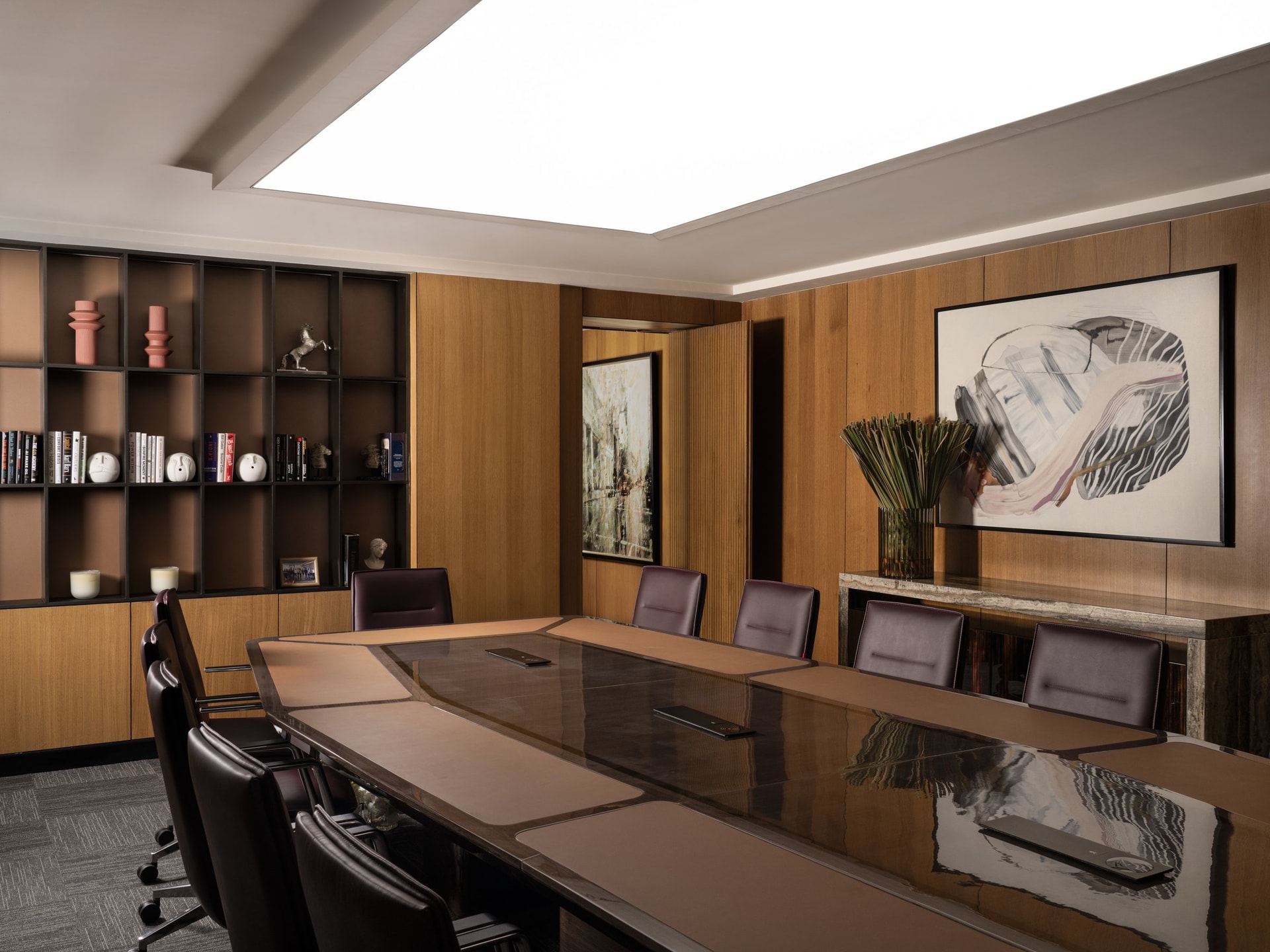 The principal boardroom, where a leather-inset table sits beneath a luminous ceiling plane