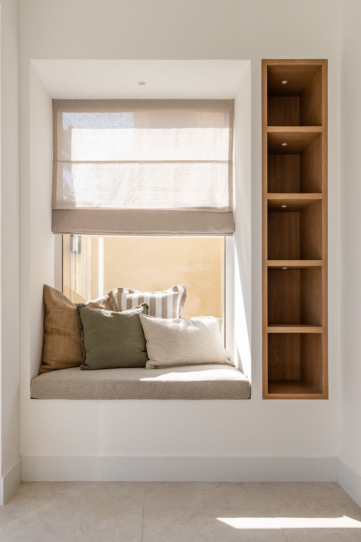 A window seat with a built-in wood niche alongside, the kind of corner that justifies its own existence