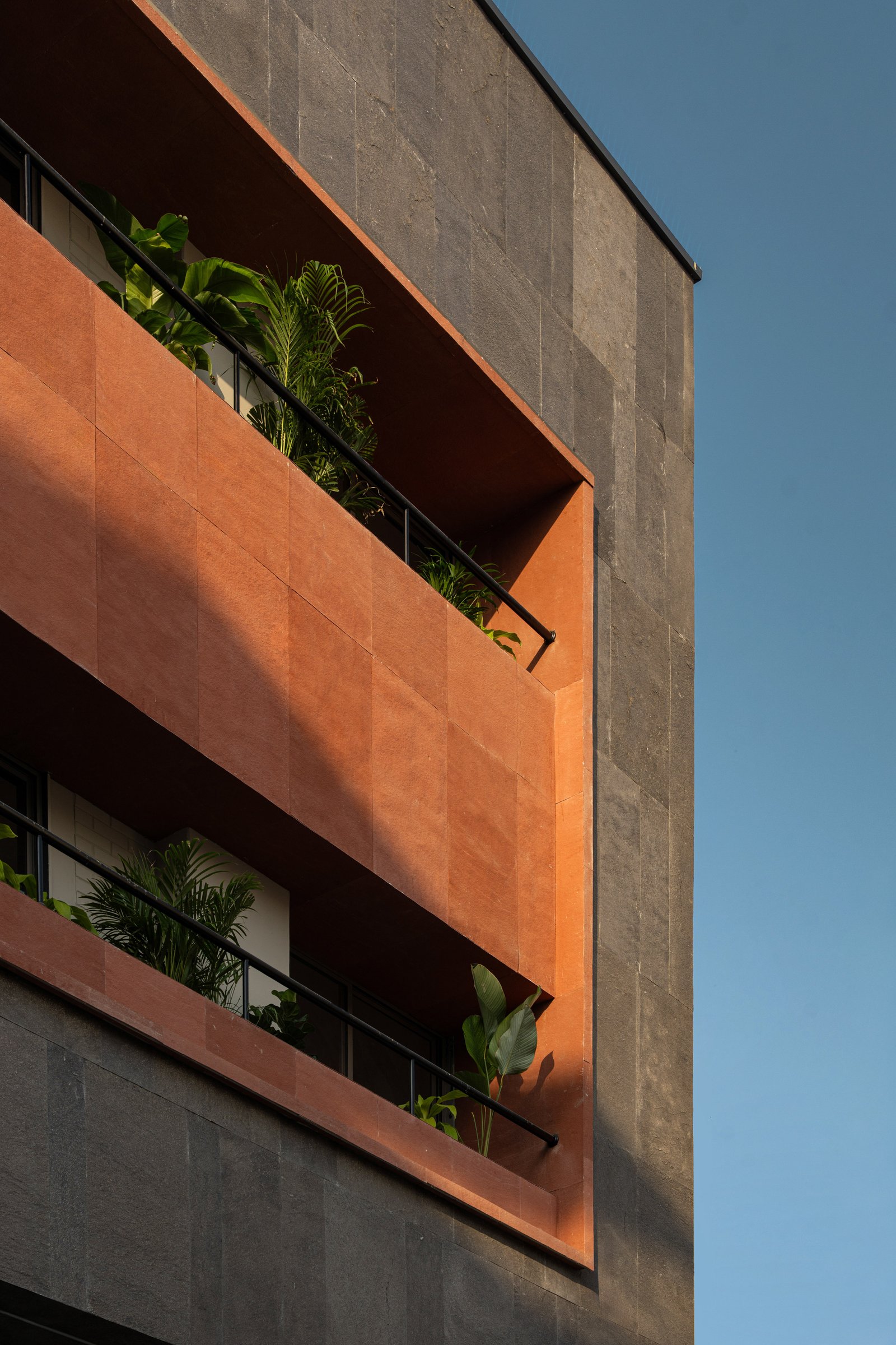A closer view of the terracotta-clad balcony bands, articulated against the grey stone surround