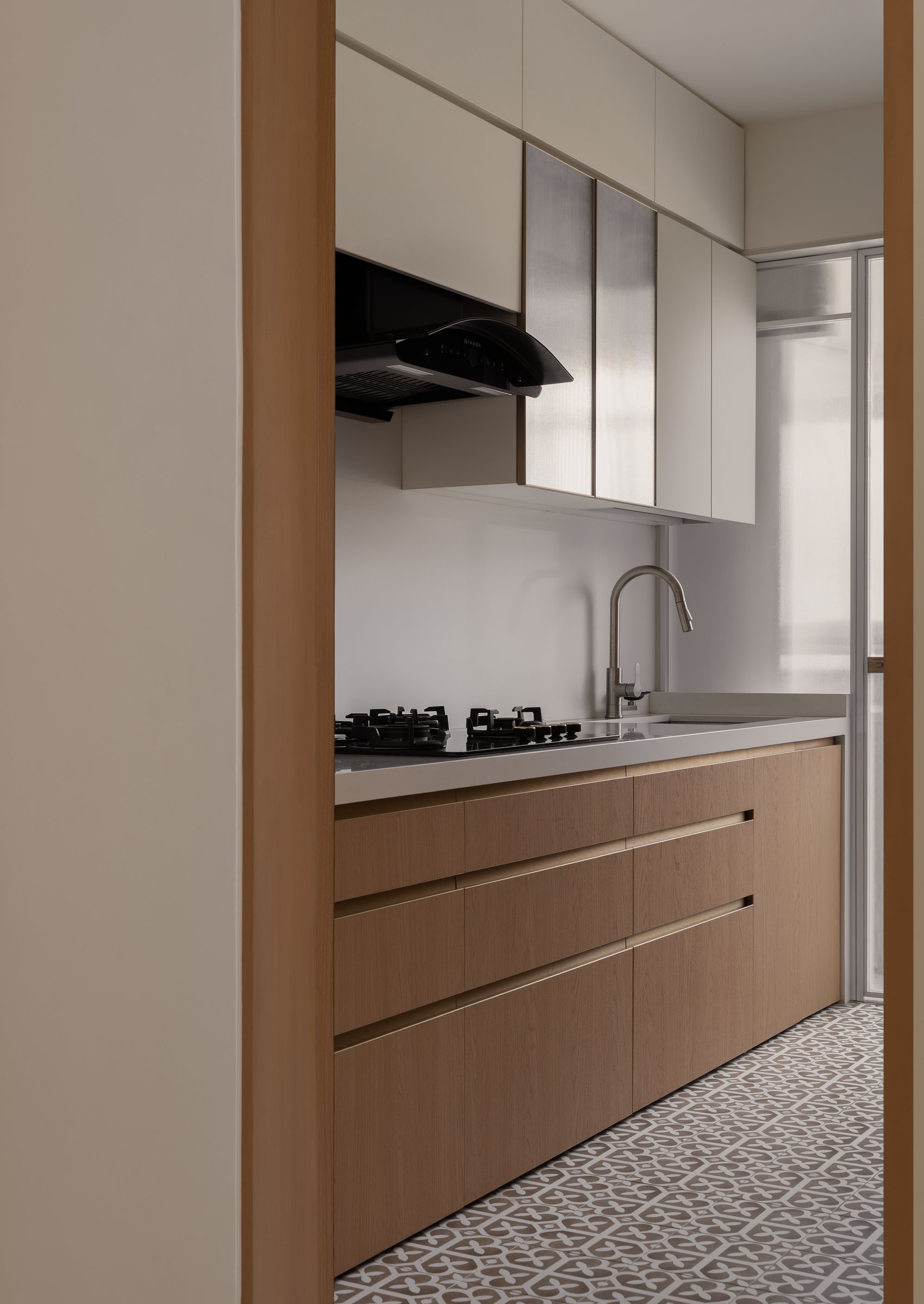 The kitchen, where warm wood-grain cabinetry and a patterned cement-look floor introduce the home's one decorative indulgence