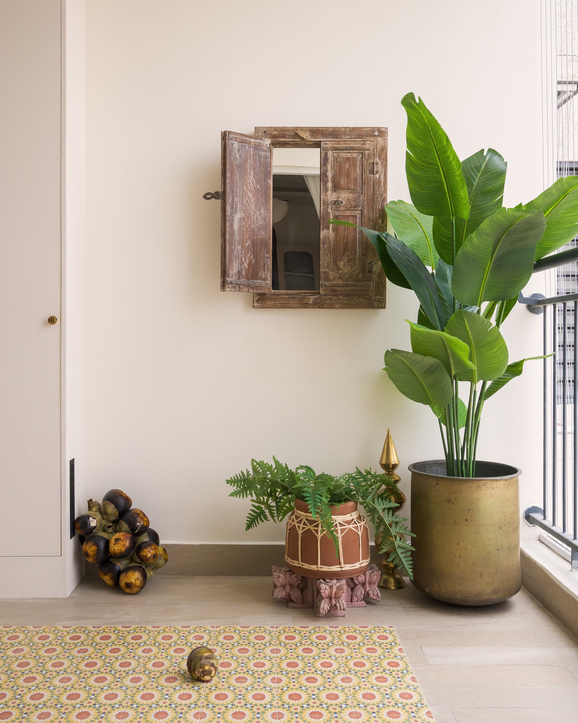 The balcony, where an antique window and a traveller's palm turn a high-rise threshold into a composed retreat