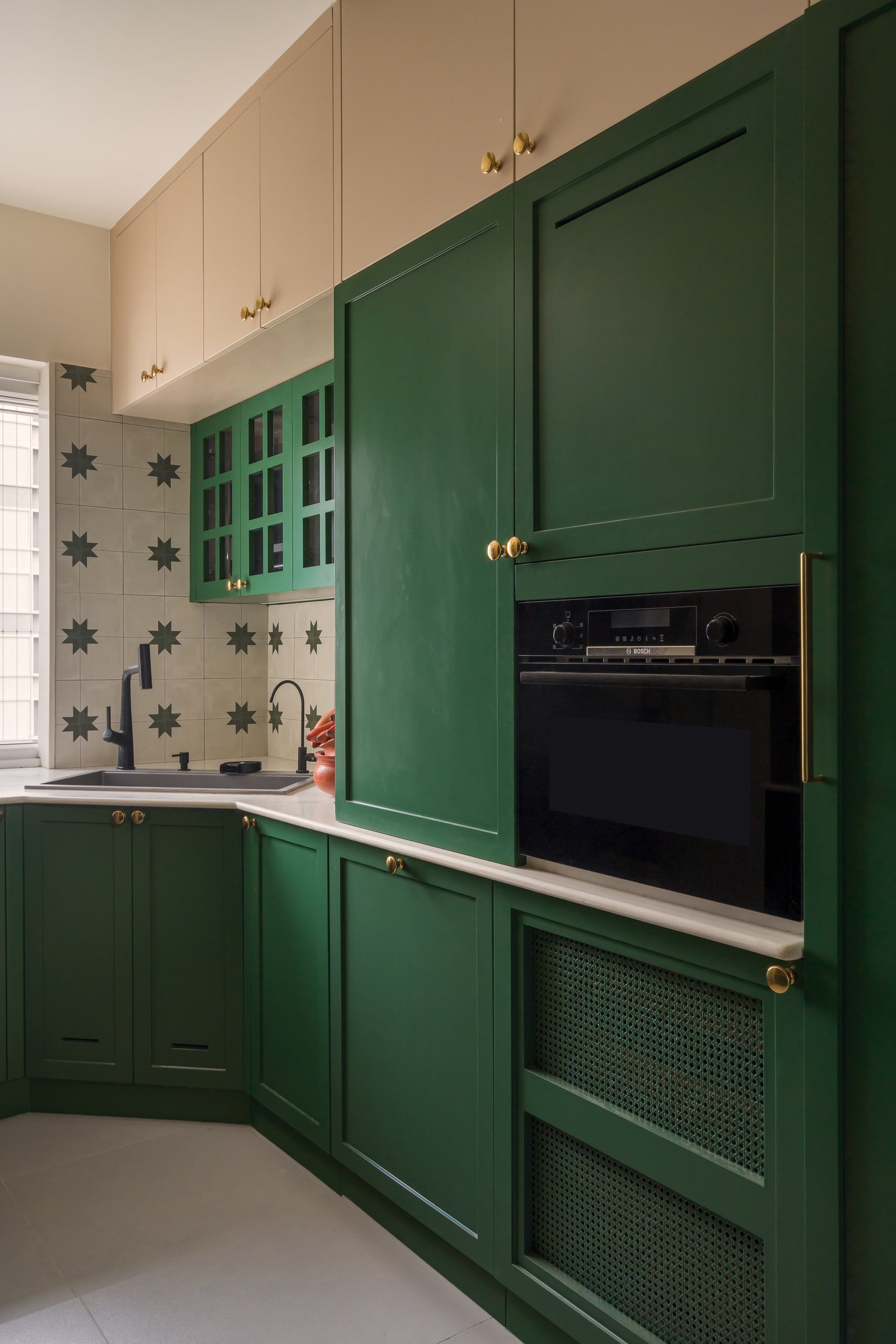 The kitchen's return, with concealed appliances and a black sink introducing a graphic counterpoint to the brass