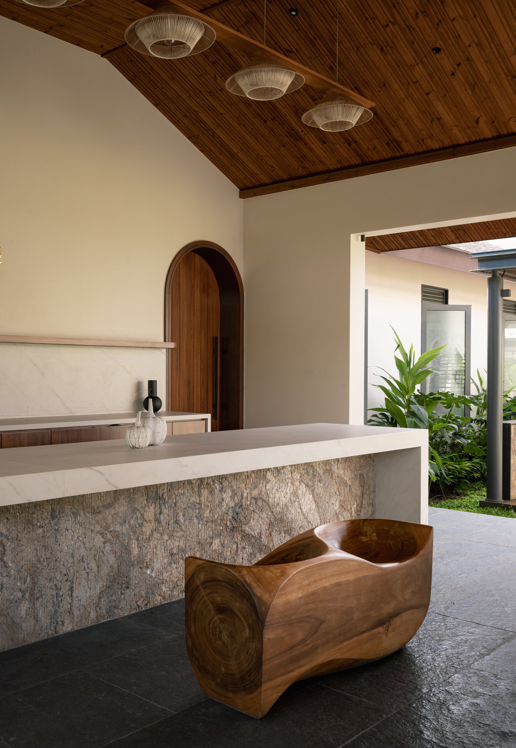 The pavilion's service counter, pairing a marble top with a veined stone base and a sculpted wood seat