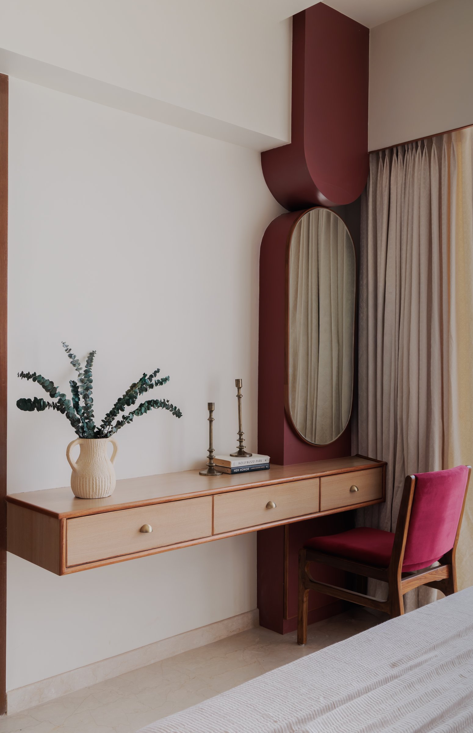 The dressing niche, where a deep burgundy alcove holds an oval mirror and a walnut floating vanity
