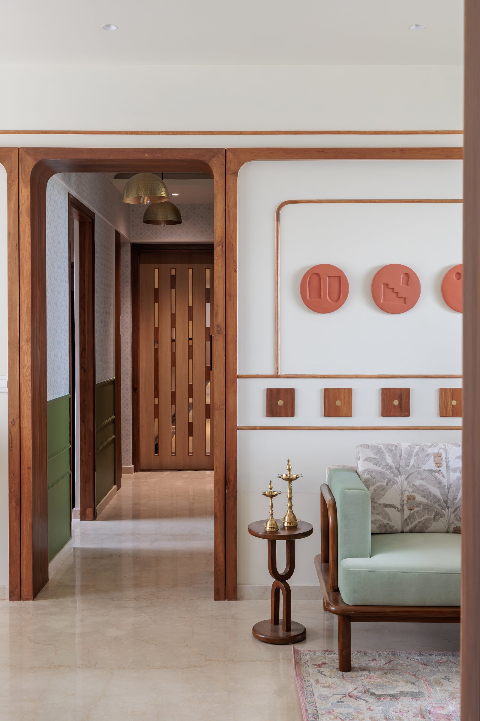 The transition from foyer to living room, framed by teak archways and anchored by the red medallion wall