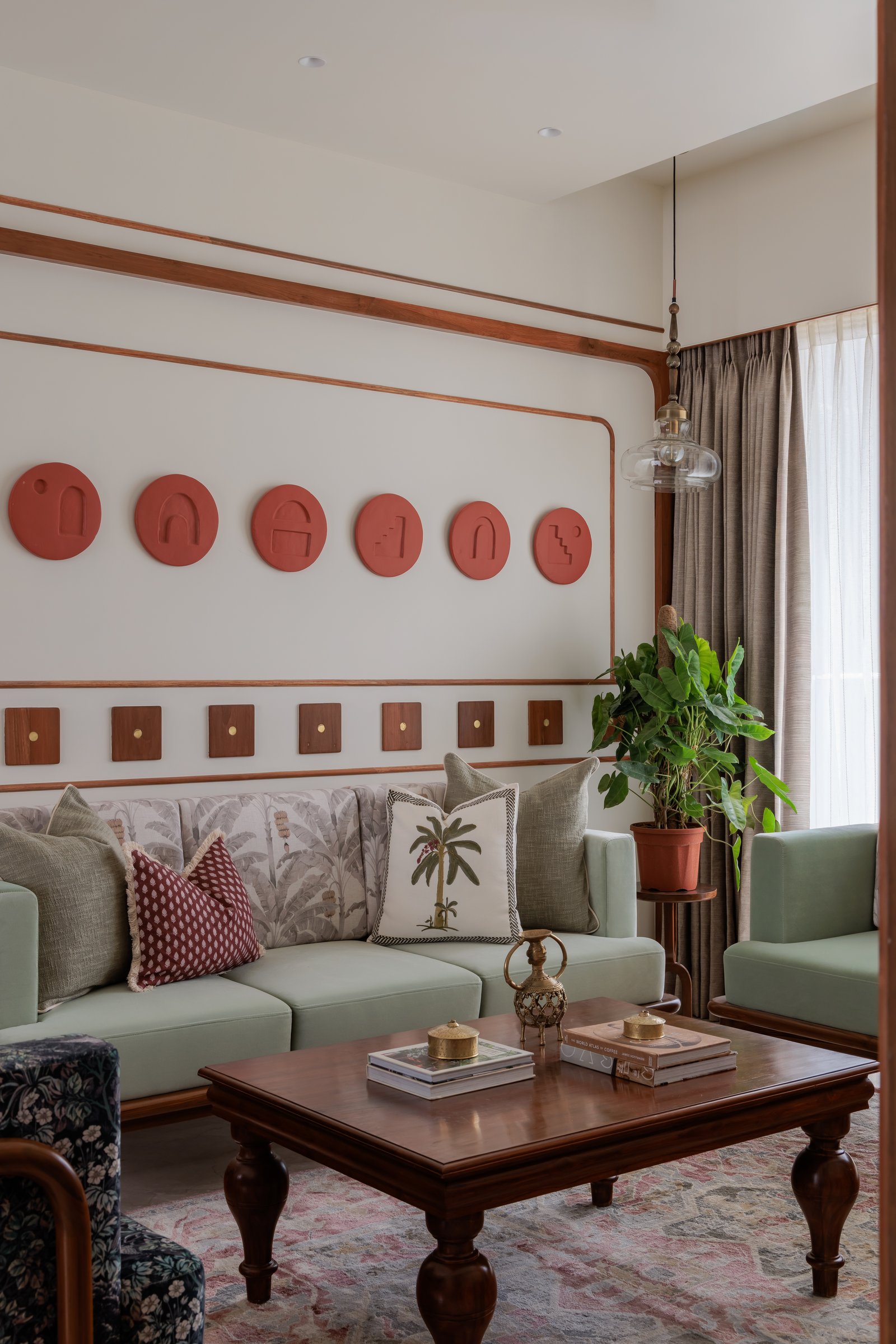 The living room seating group, resolved around a low teak coffee table with turned baluster legs and a muted rose rug