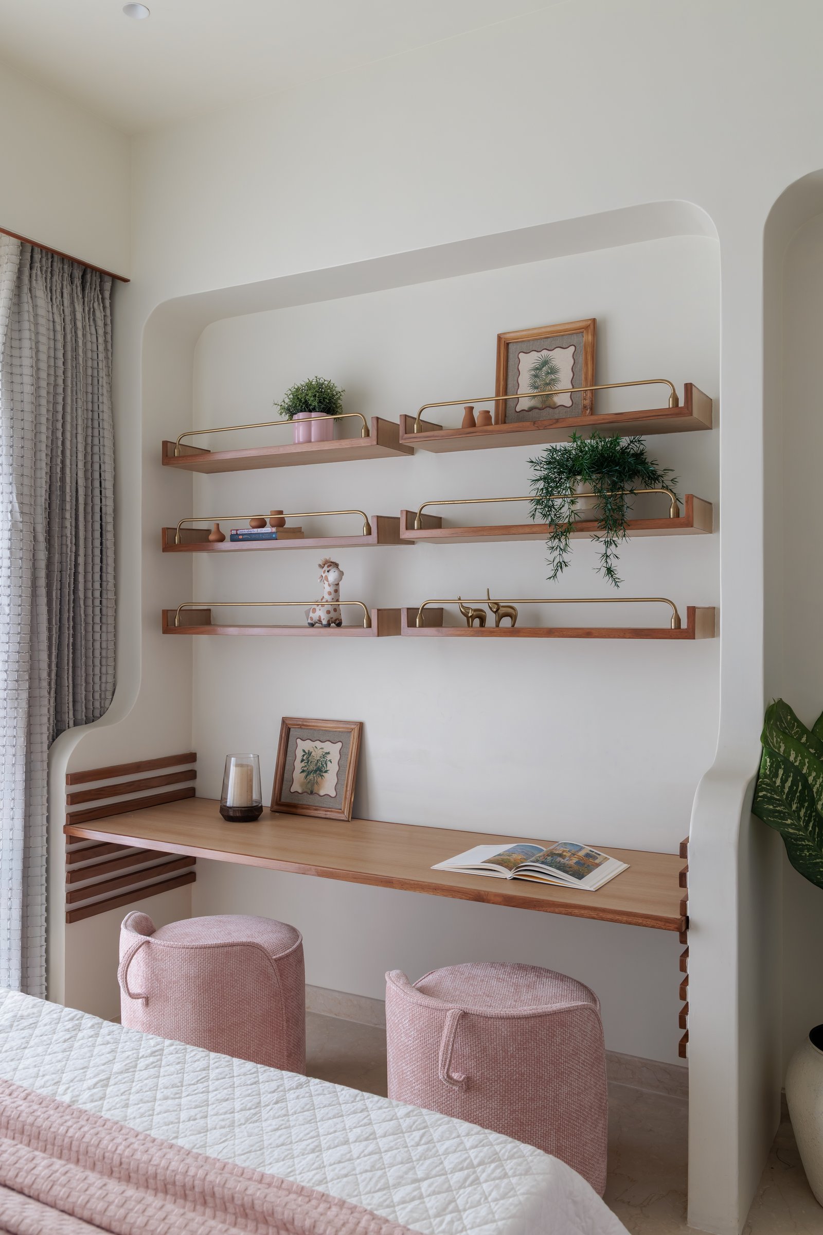 The curved study nook, where walnut shelves with slim brass rails frame a writing surface tucked into the bedroom