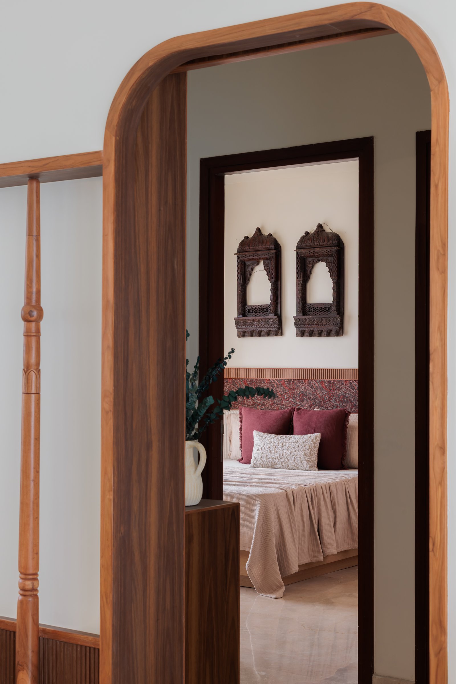 The master bedroom's threshold, framed by a rounded teak archway detailed with a slender turned baluster