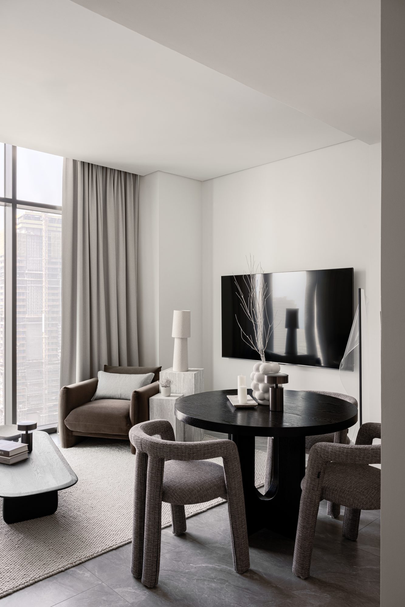 The Peninsula One living room, with the Dubai skyline framed through floor-to-ceiling curtains — round forms, warm textures, and the view as the interior's originating idea.
