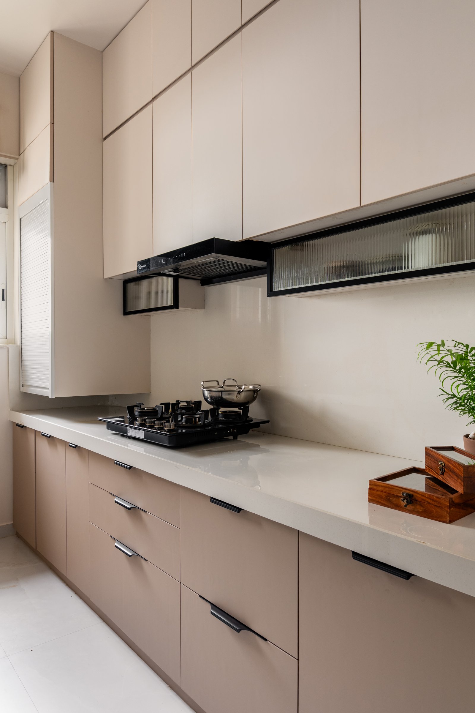 The galley kitchen, where blush lower cabinetry meets cream uppers along a light quartz counter kept deliberately clear
