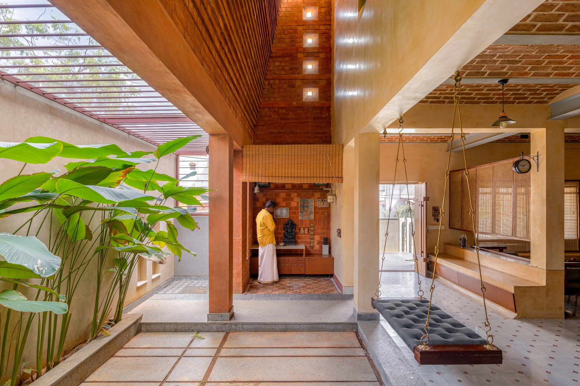 The pooja space, held within a double-height brick shaft that draws daylight down through square openings