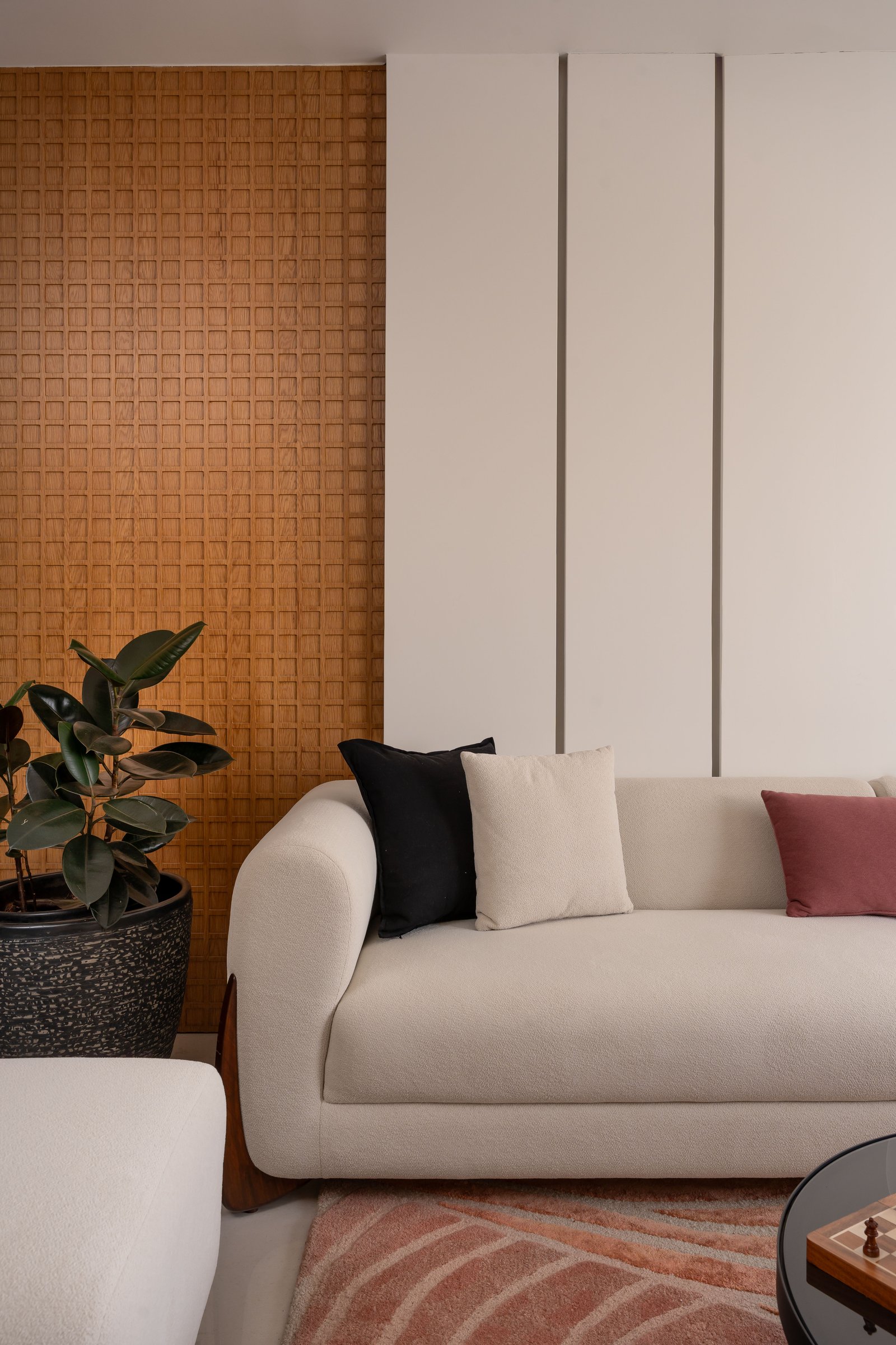 A closer view of the living room's material dialogue between panelled ivory and warm woven timber