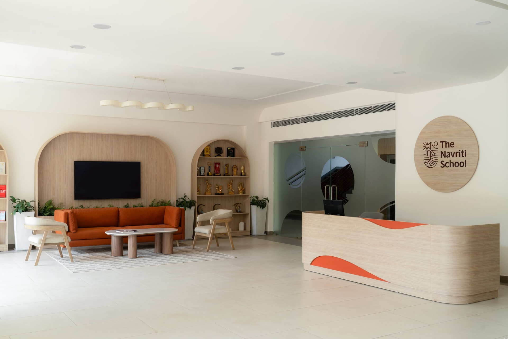 The reception, where a curved oak desk inset with orange-red panels sits beneath an arched media niche and a circular signage disc