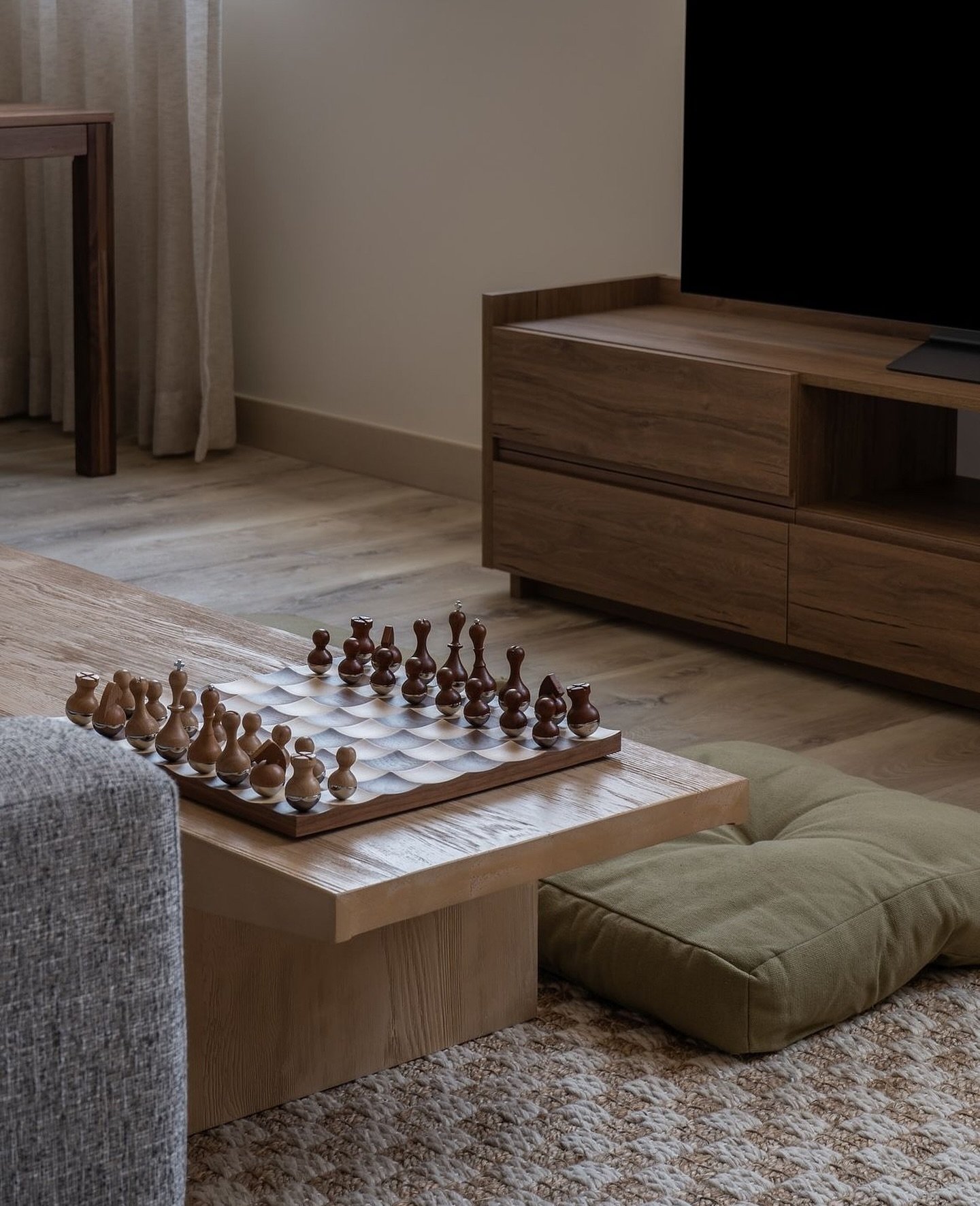 A close view of the living vignette, walnut console, woven rug and quiet tonal balance.