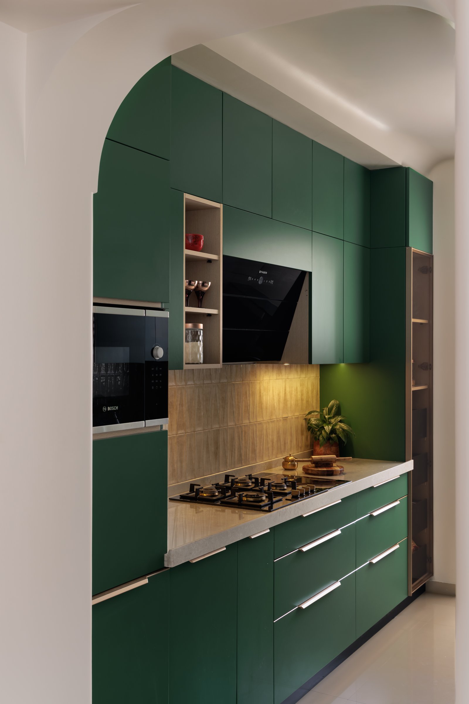 The kitchen, where deep forest green cabinetry meets a warm wood-lined niche