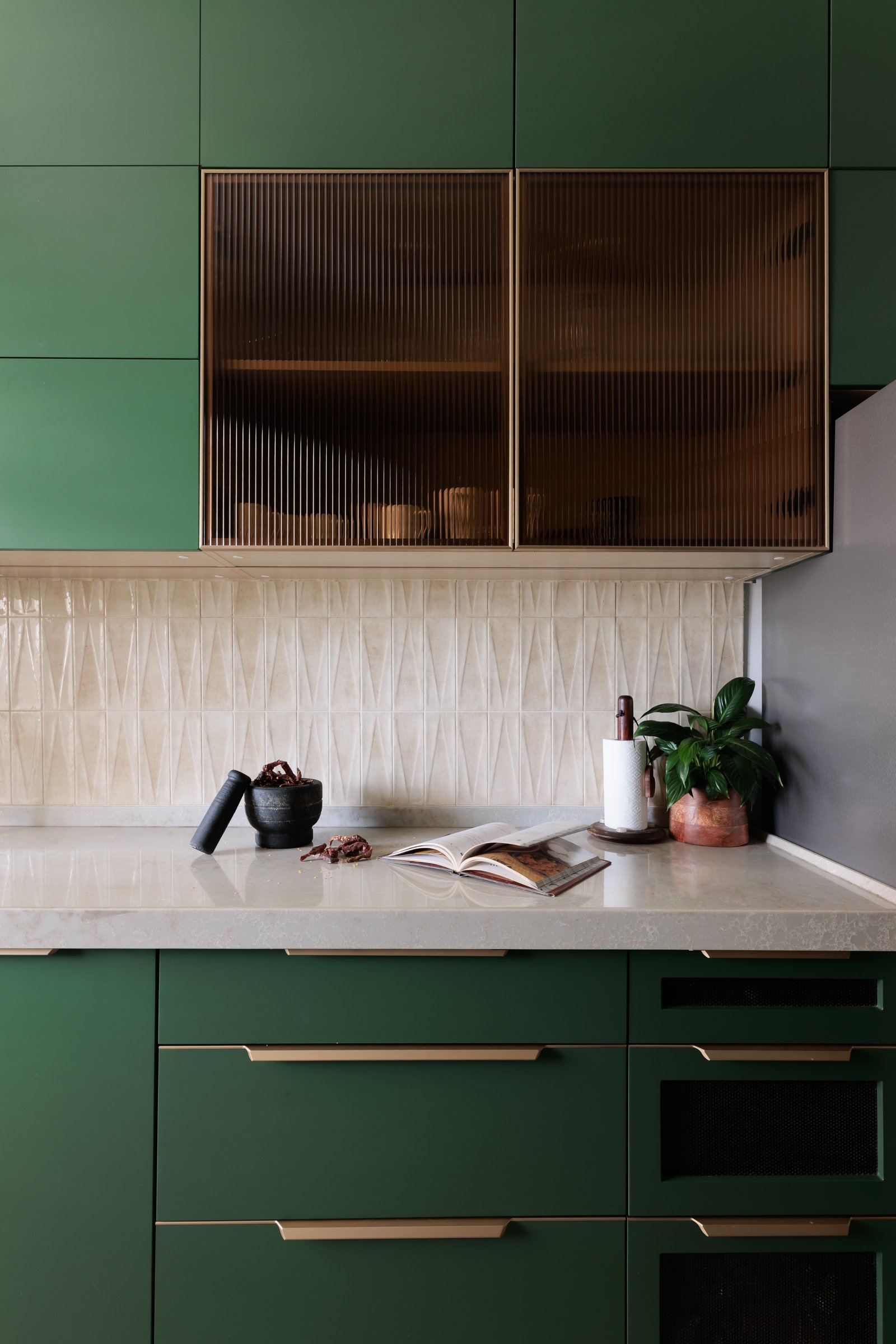 Fluted amber glass fronts and a textured backsplash sharpen the kitchen's disciplined palette