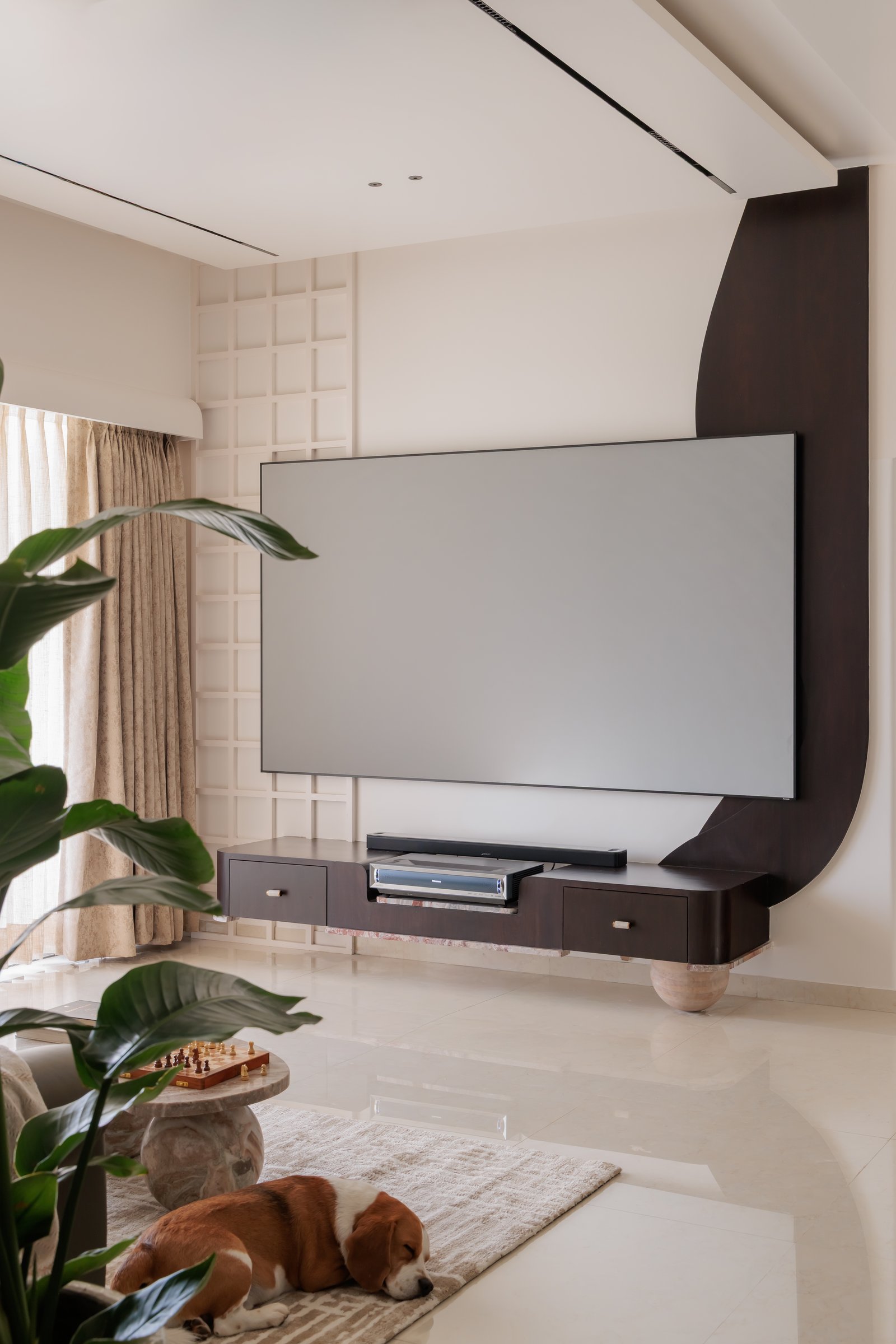 The dark media console, its curved rear panel absorbing the television into the architecture