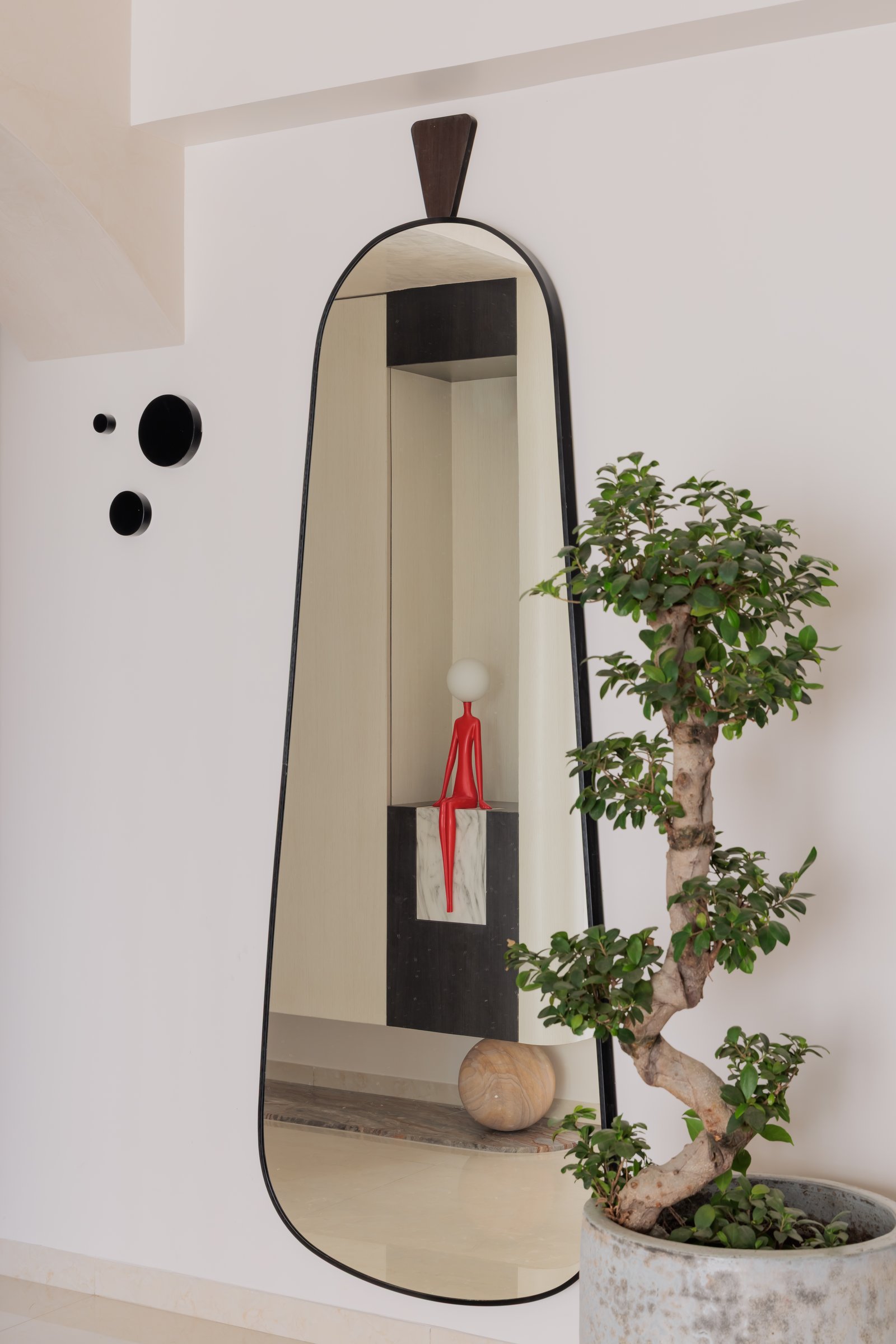 An elongated mirror and a bonsai bring quiet weight to the entry composition