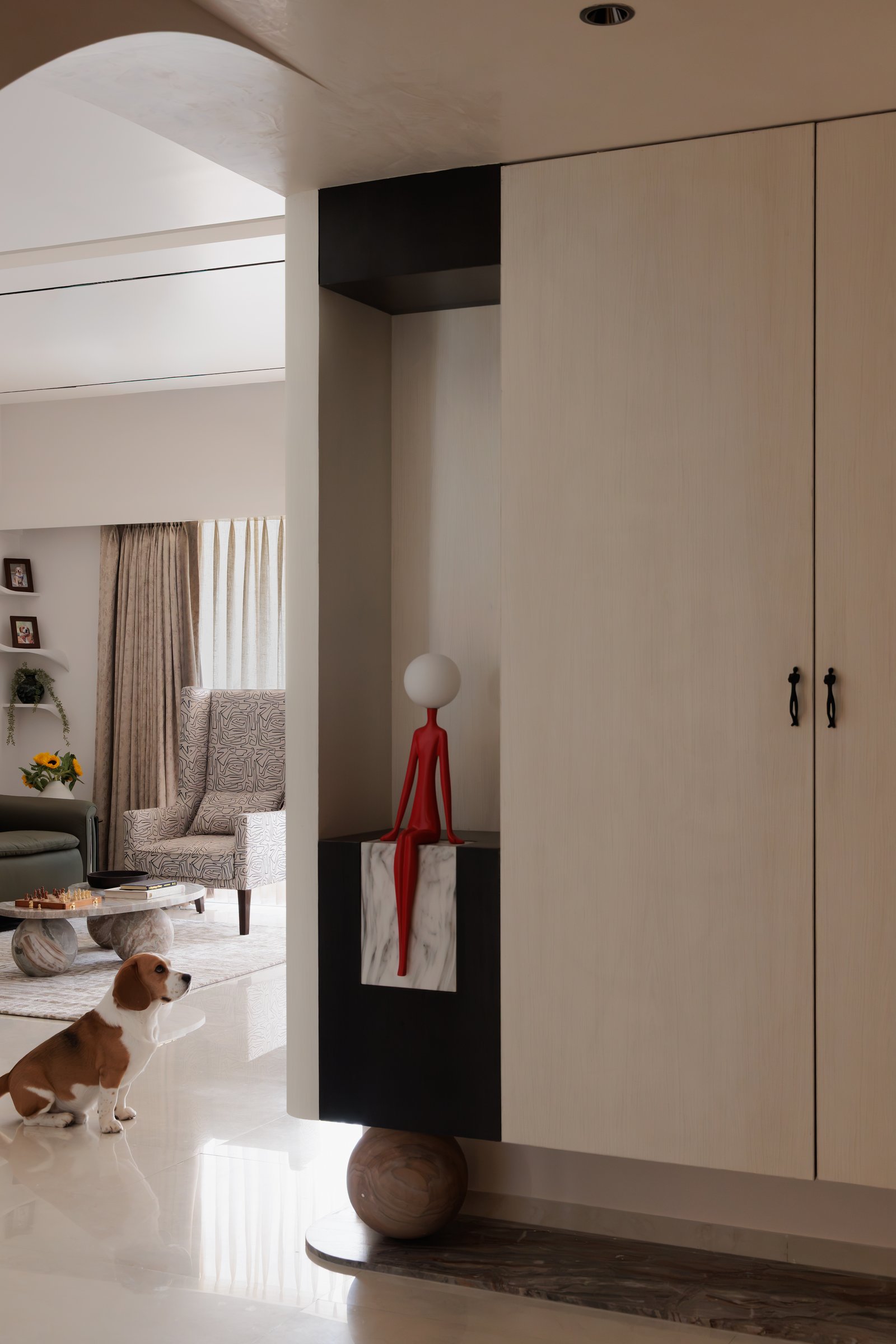 The foyer, where a red figurative sculpture on a marble plinth sets the home's playful, collected tone