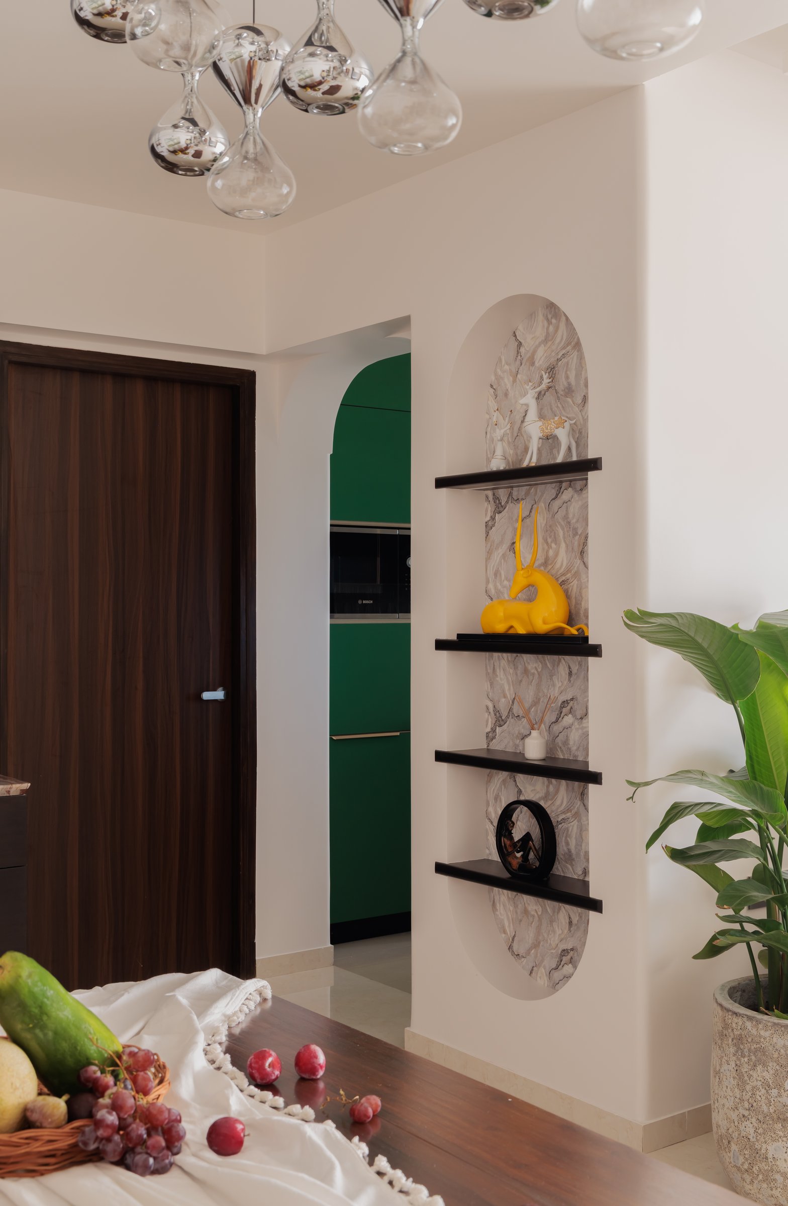 An arched niche previews the kitchen's deep green palette through the doorway beyond