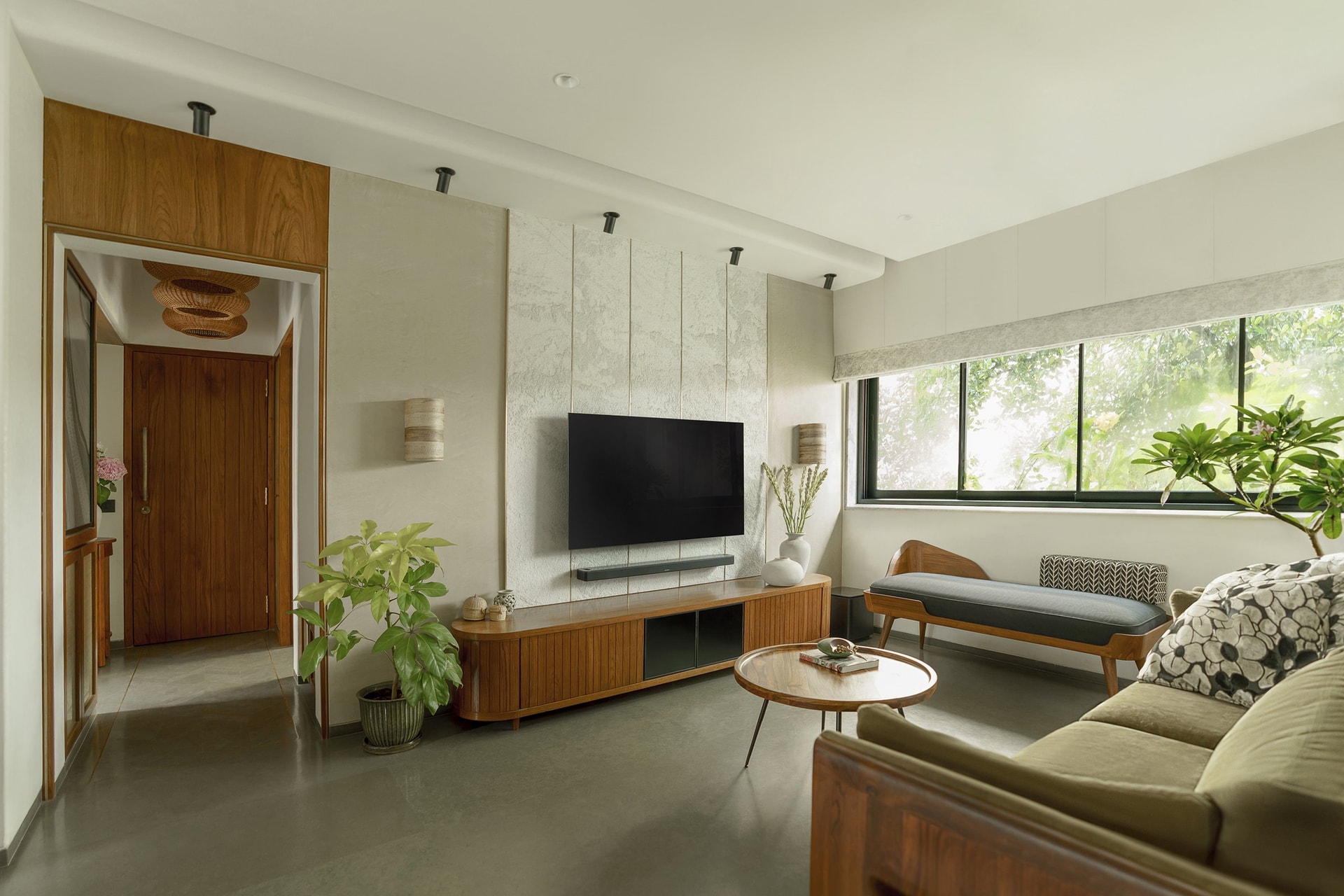 The media wall in hand-textured lime plaster, articulated by slim vertical inlays that recall Kutchhi interiors