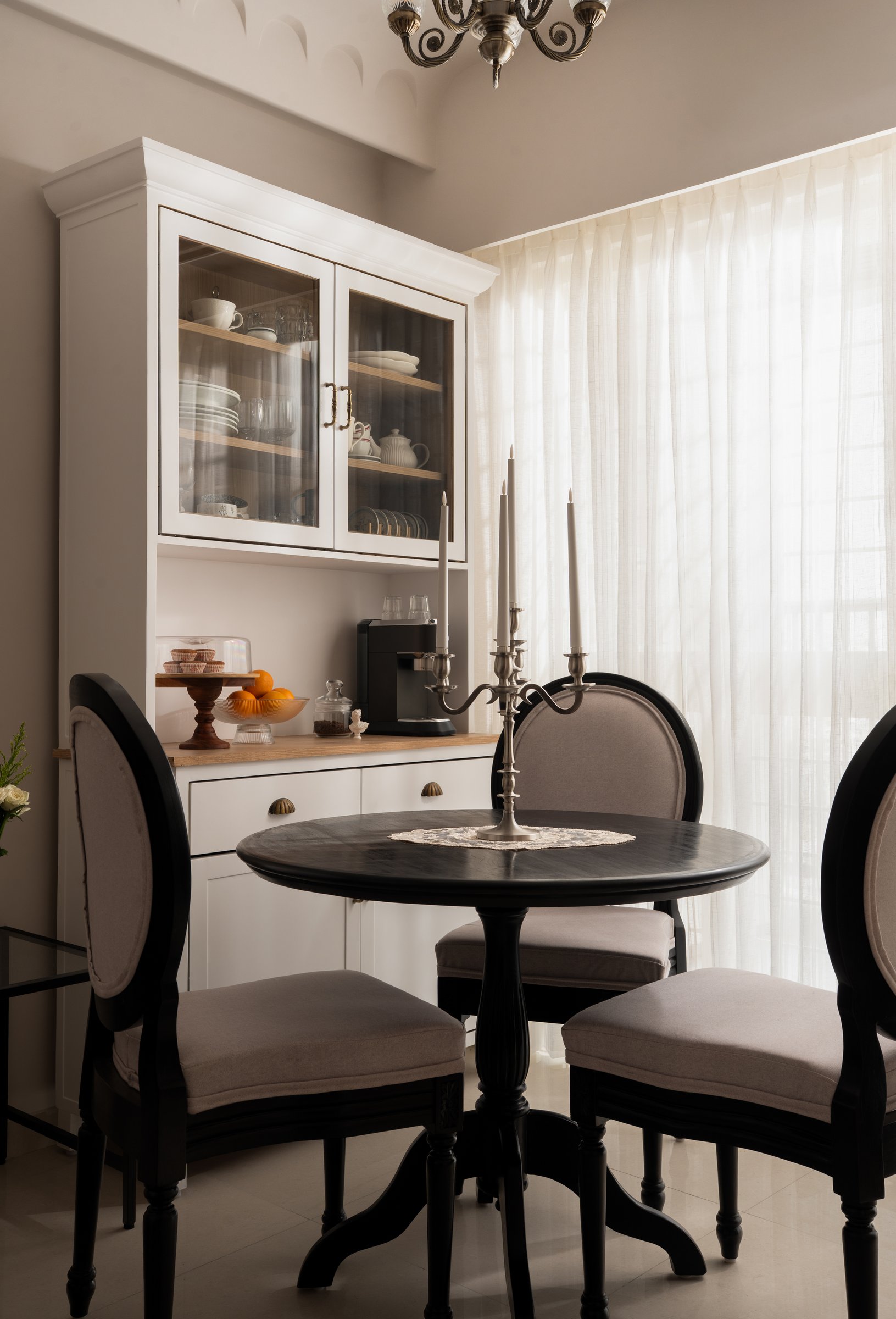The dining zone anchored by a slim white crockery unit and a round black pedestal table