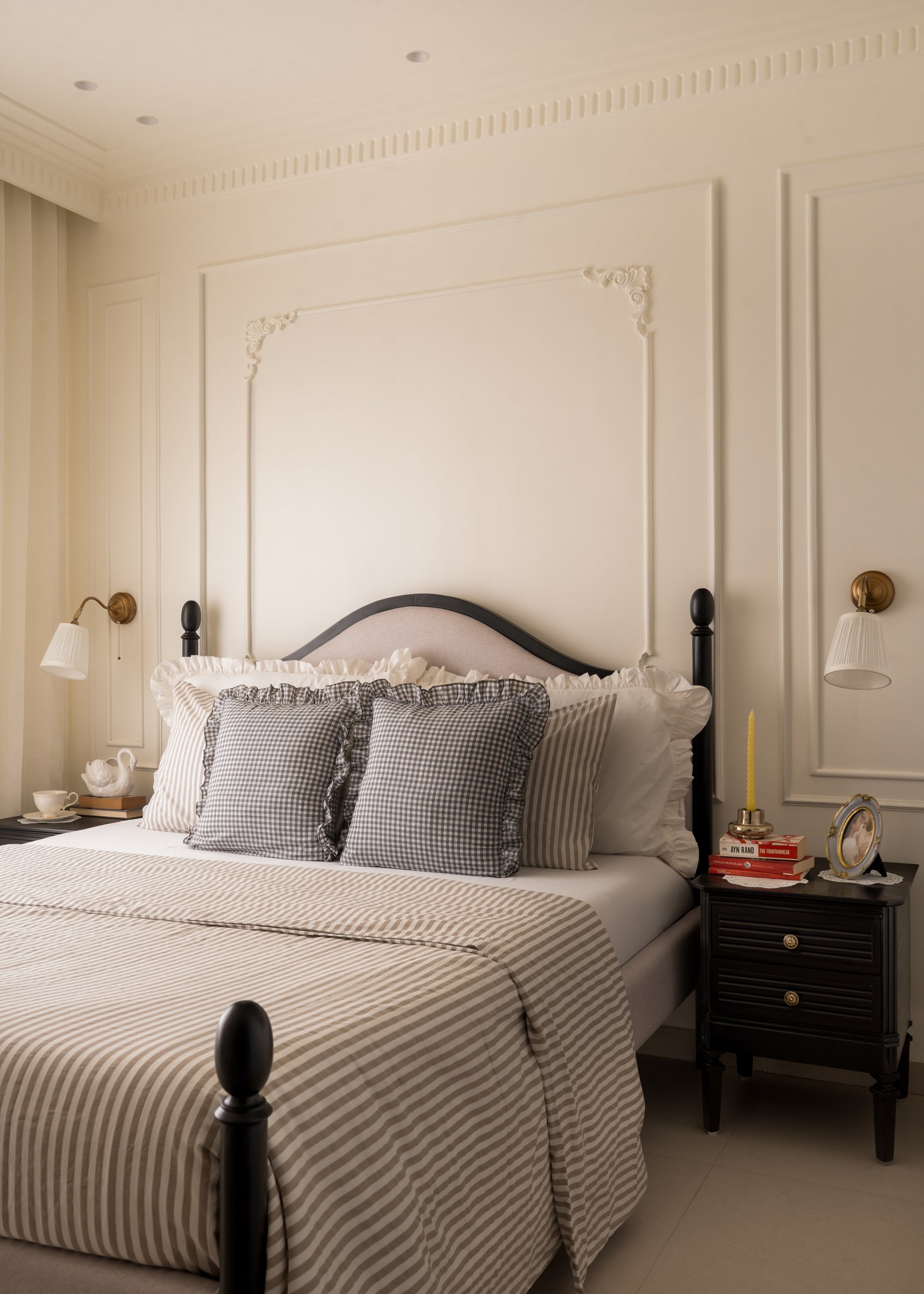 The bedroom, its panelled wall and dark-framed bed carrying the home's European register to its fullest expression