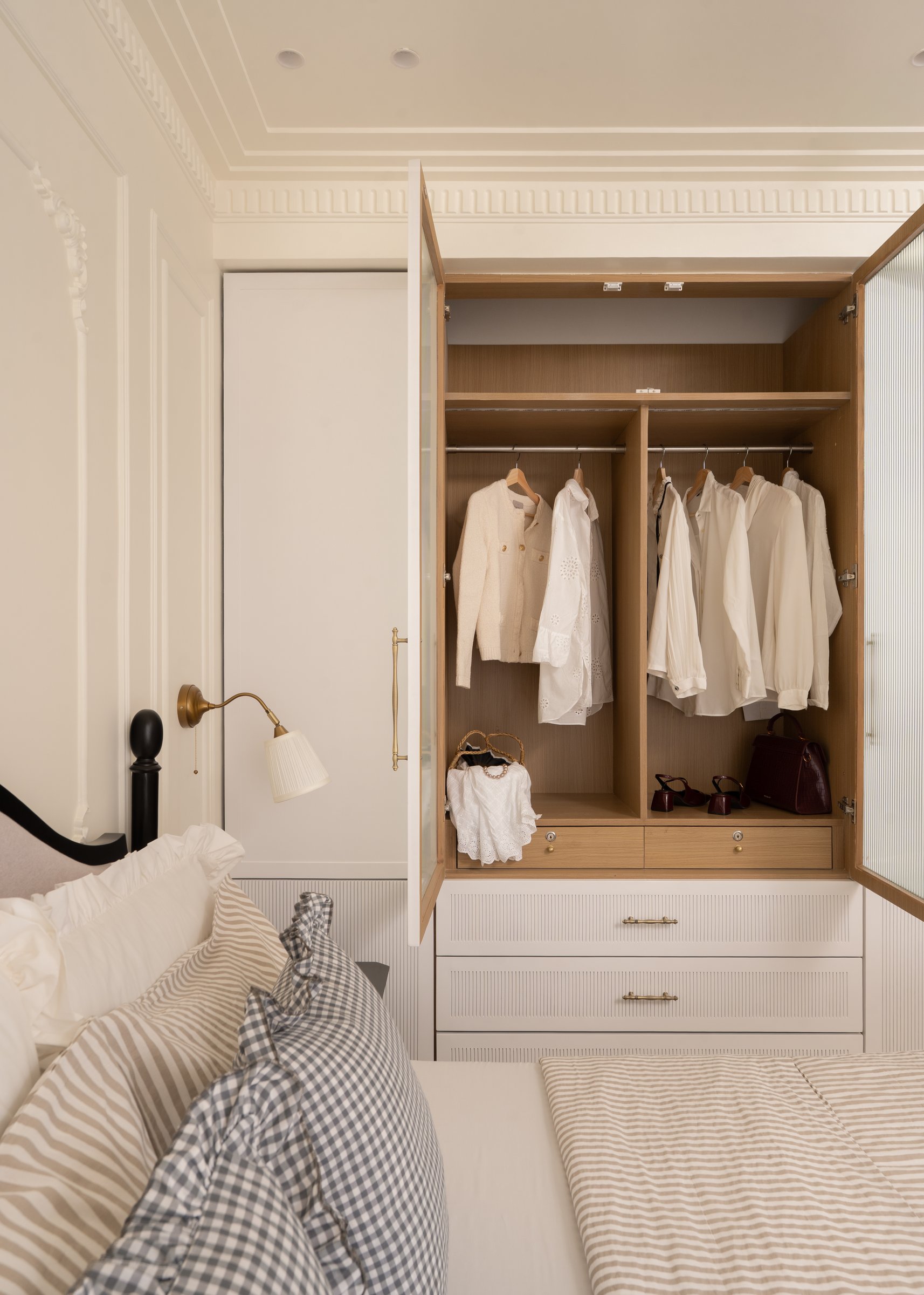 The wardrobe opened to reveal warm timber interiors and a small edited selection of clothing