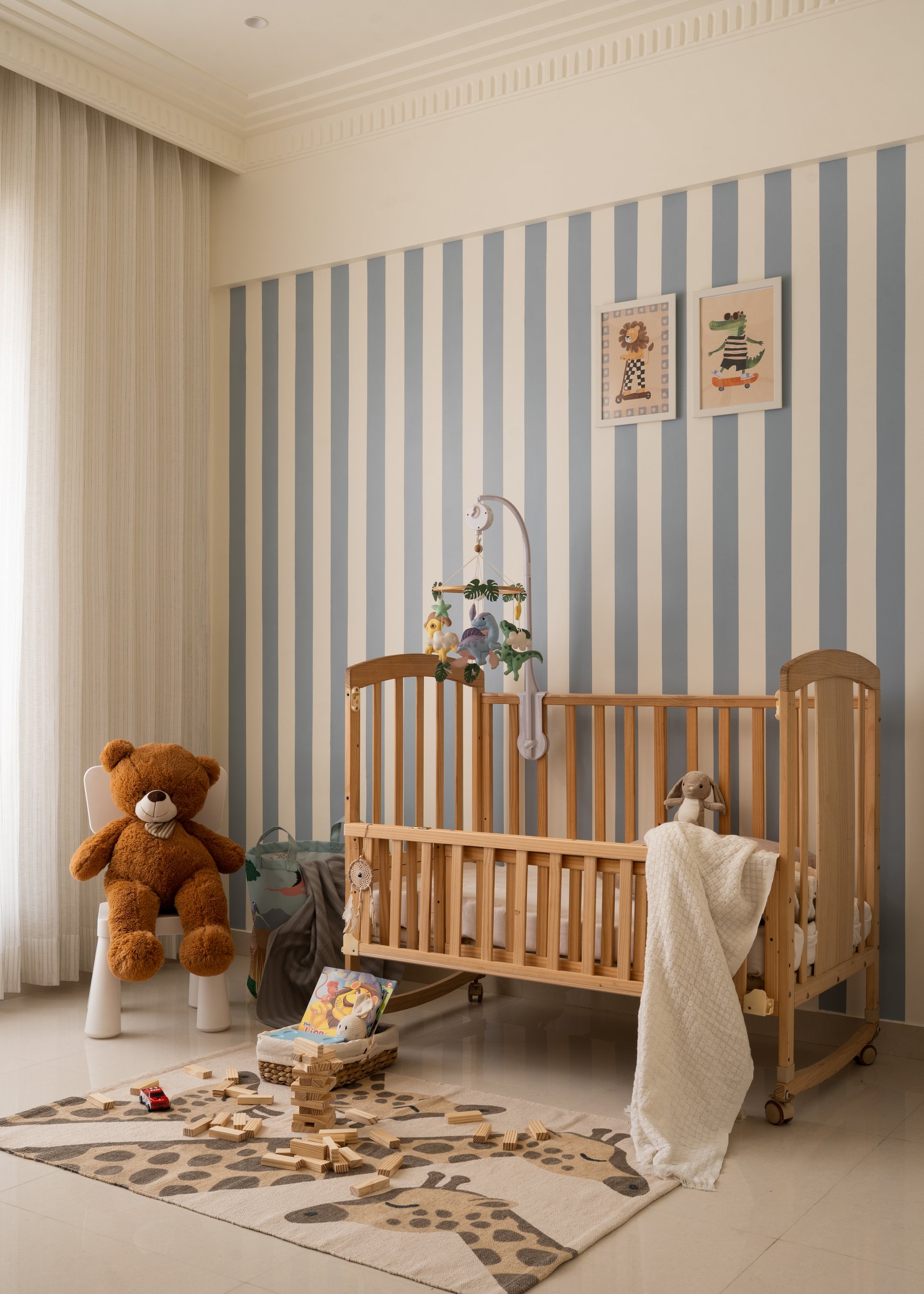 The nursery, wrapped in blue and cream vertical stripes, accommodating the family's next chapter
