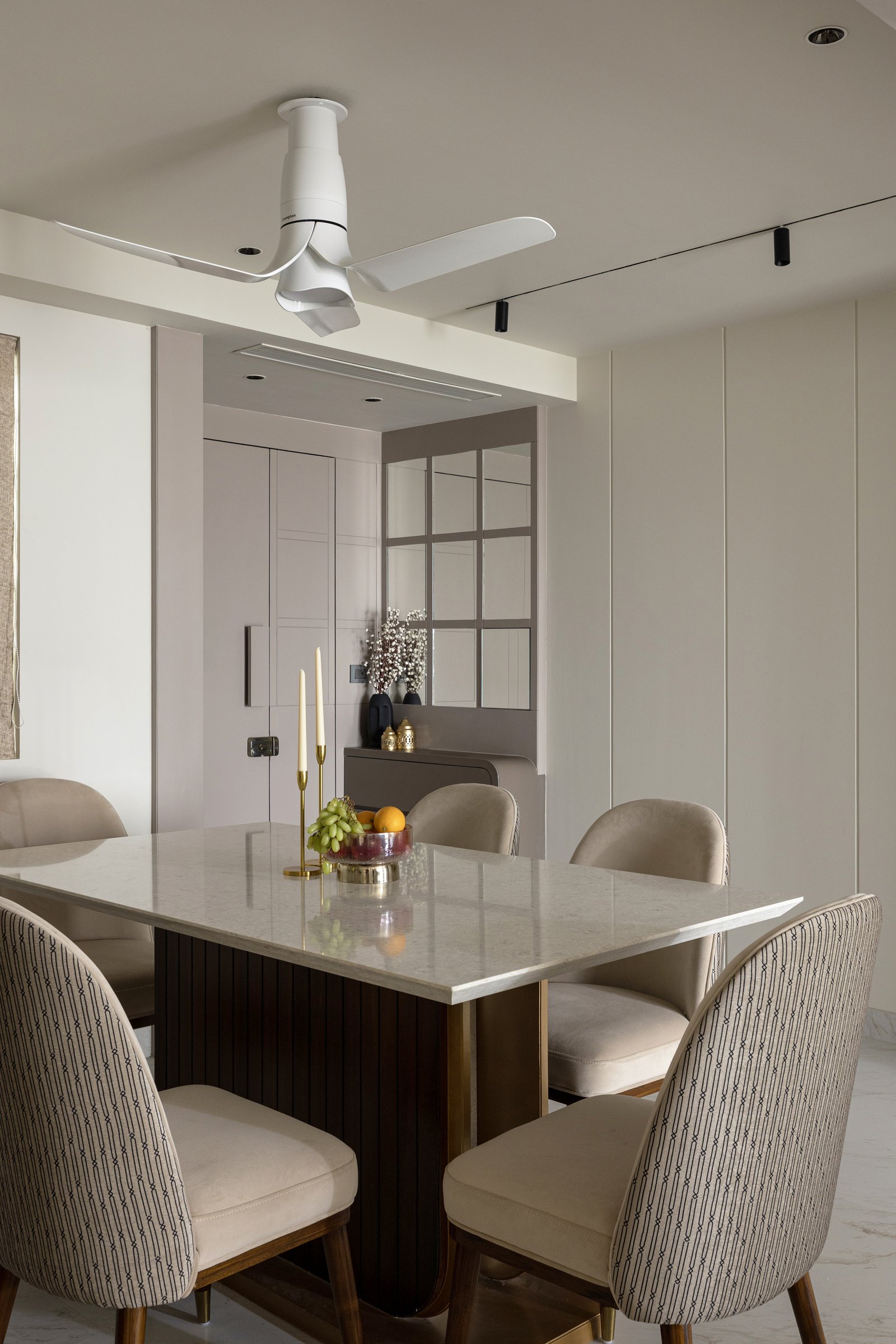 The dining area, where a fluted dark wood base and mirrored grid partition lend intimacy to the shared volume