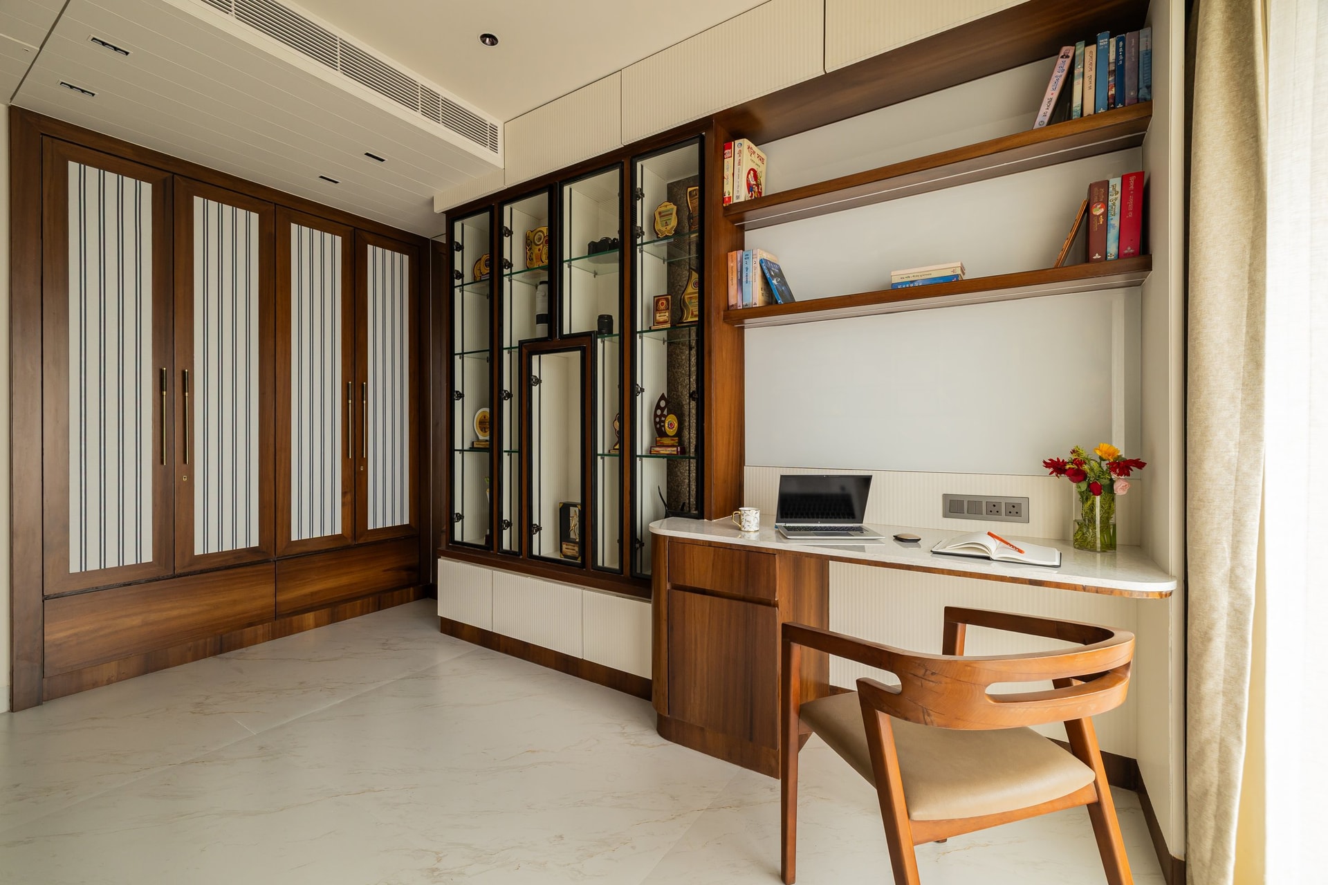 The study, its warm wood-framed wardrobes and metal-framed display cabinet giving the room its tactile register