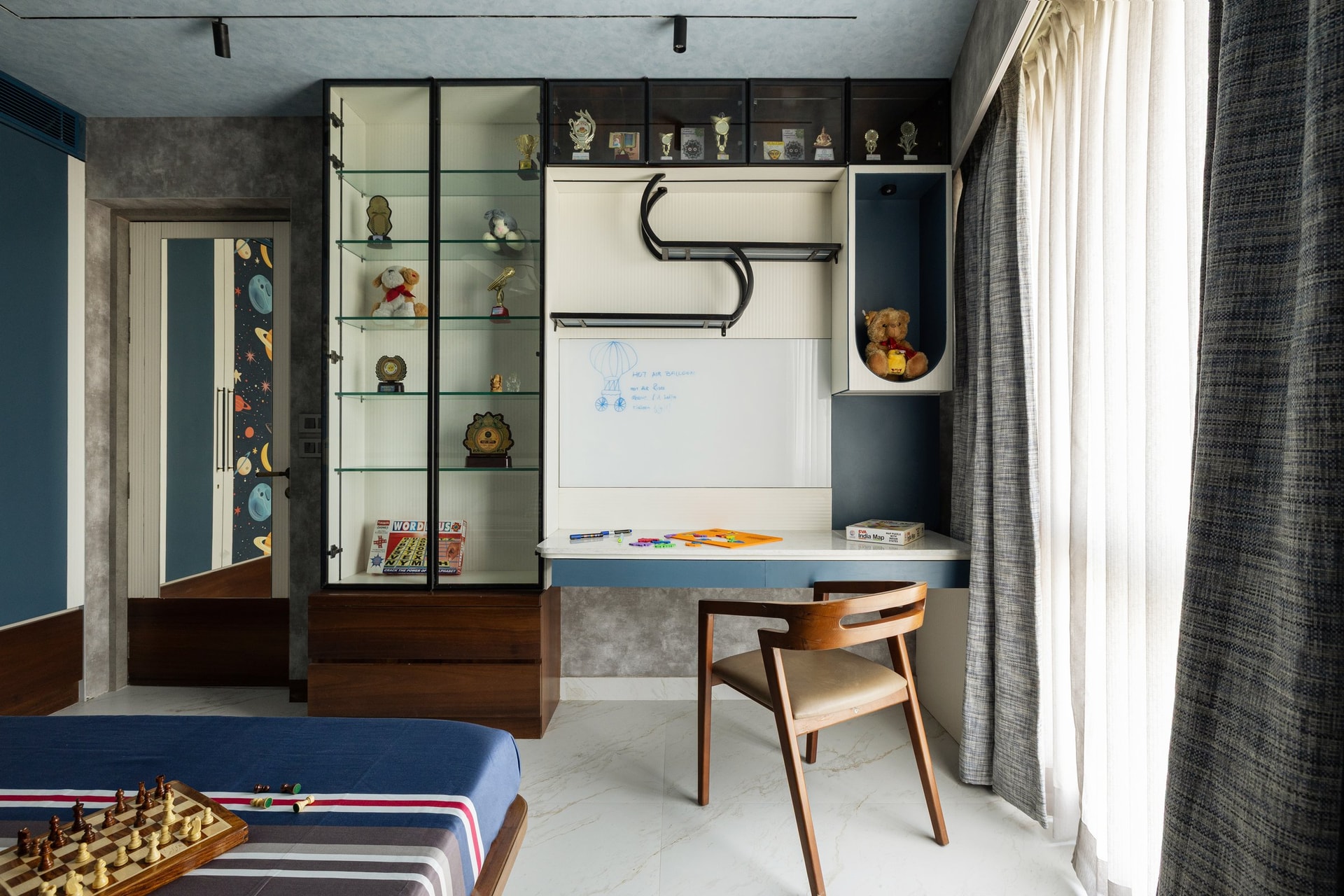 The study side of the same room, treated as a compact working corner with glazed display and whiteboard