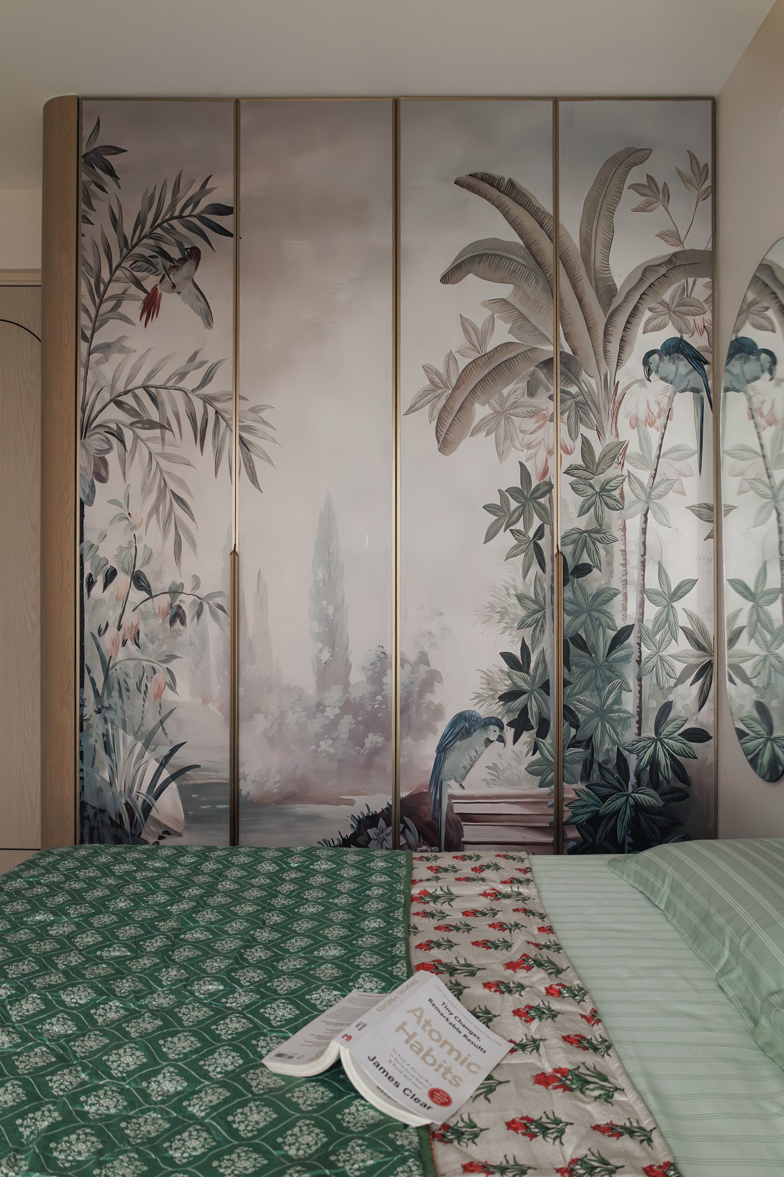 The second bedroom, its wardrobe transformed into a painted landscape mural divided by slim brass reveals
