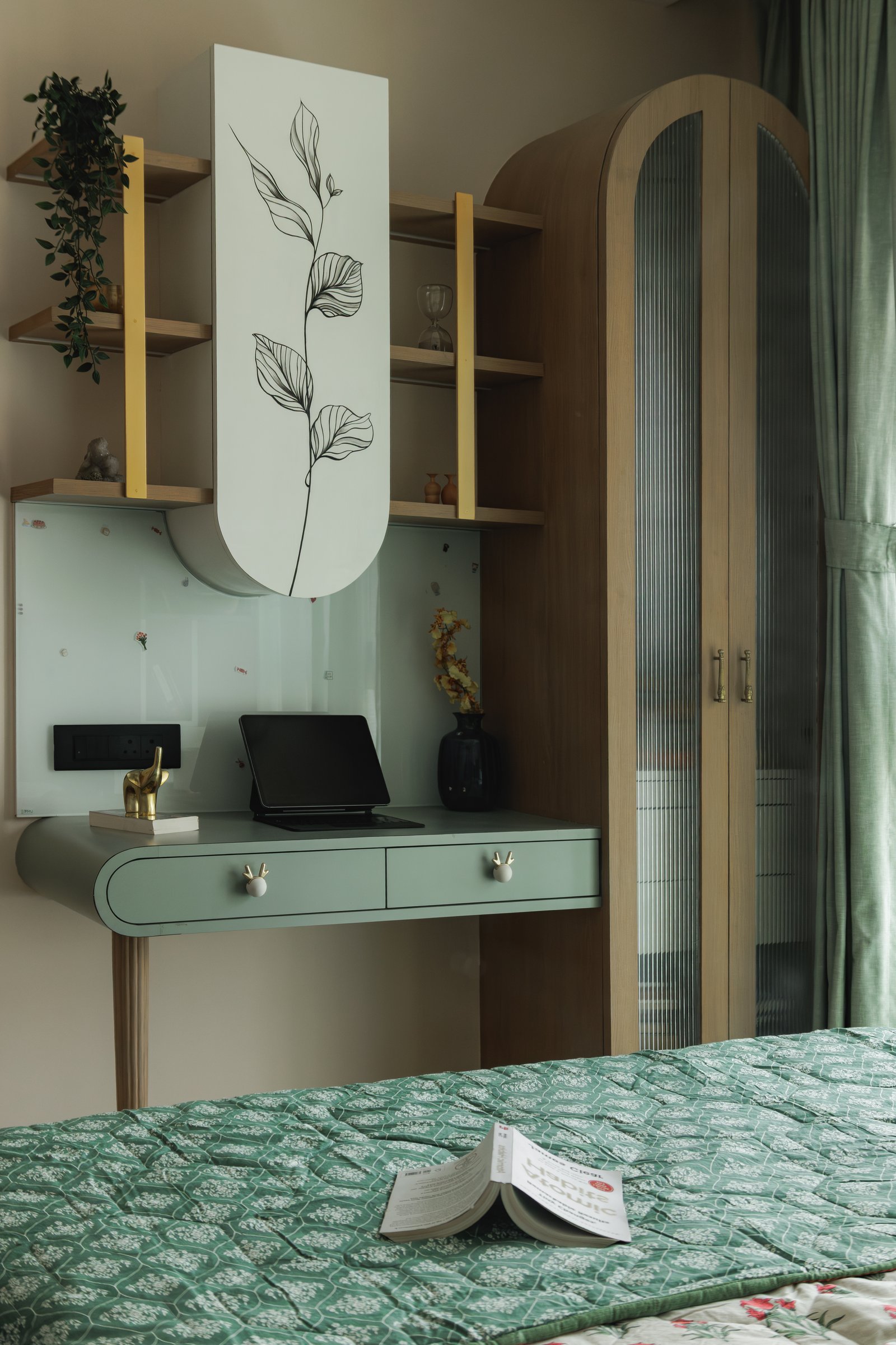 The dressing corner in muted sage green, with a curved desk and a fluted glass wardrobe alongside