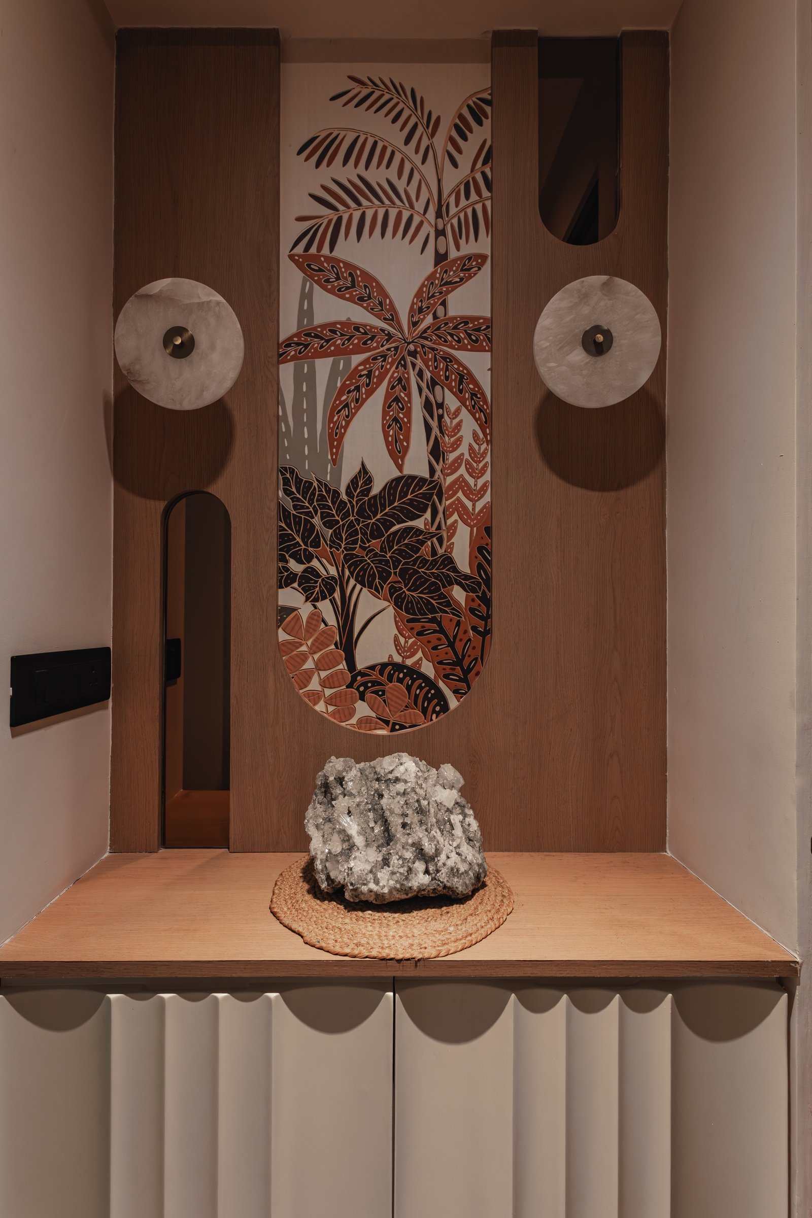 The entry niche, framed in warm oak and anchored by a raw crystalline specimen on a woven jute mat