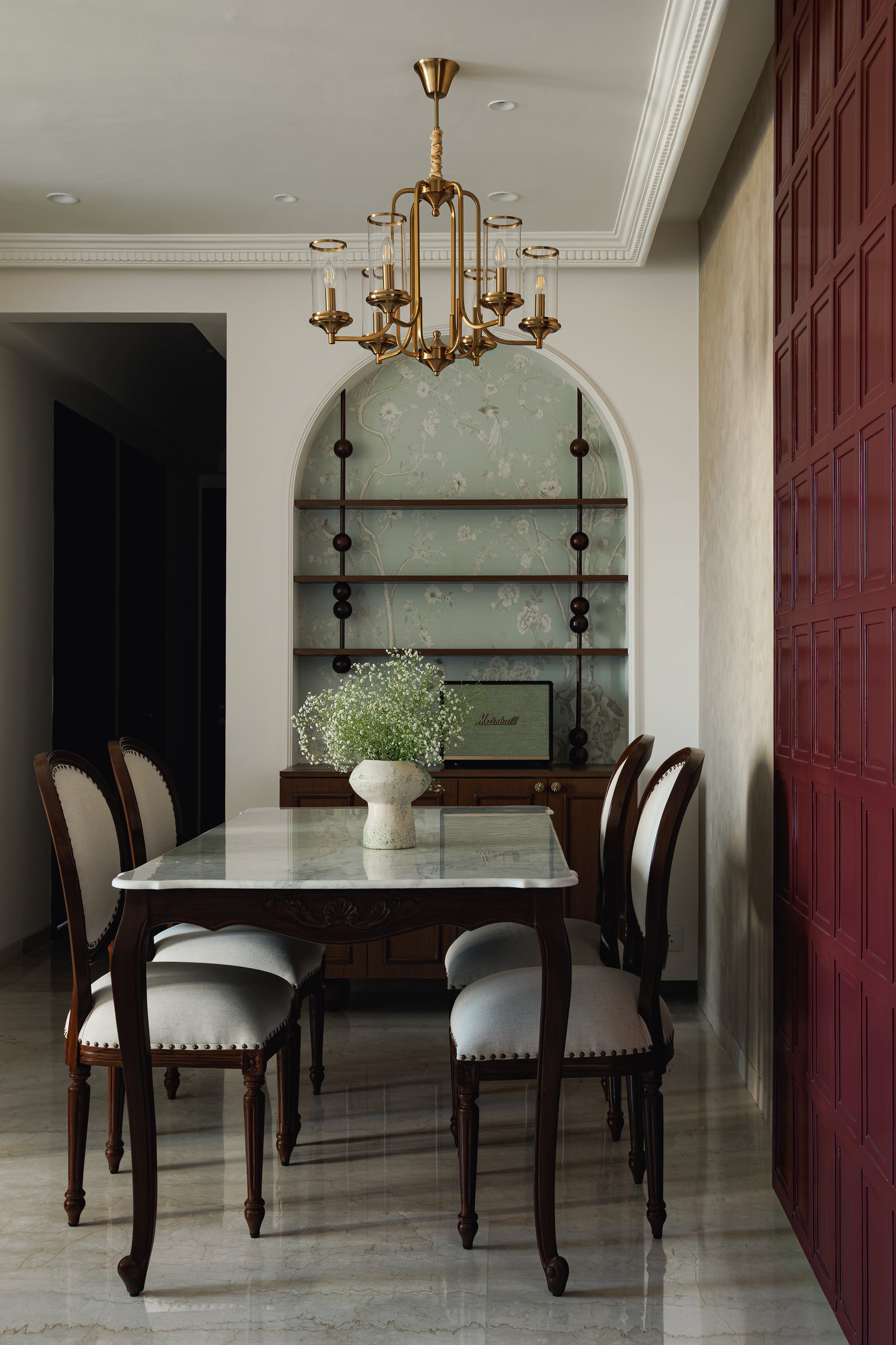 The dining alcove, anchored by a marble-topped carved table and an arched display niche