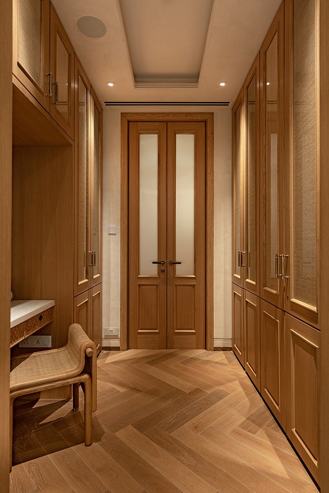 The walk-in wardrobe, lined with floor-to-ceiling panelled oak cabinetry and terminating in frosted-glass doors