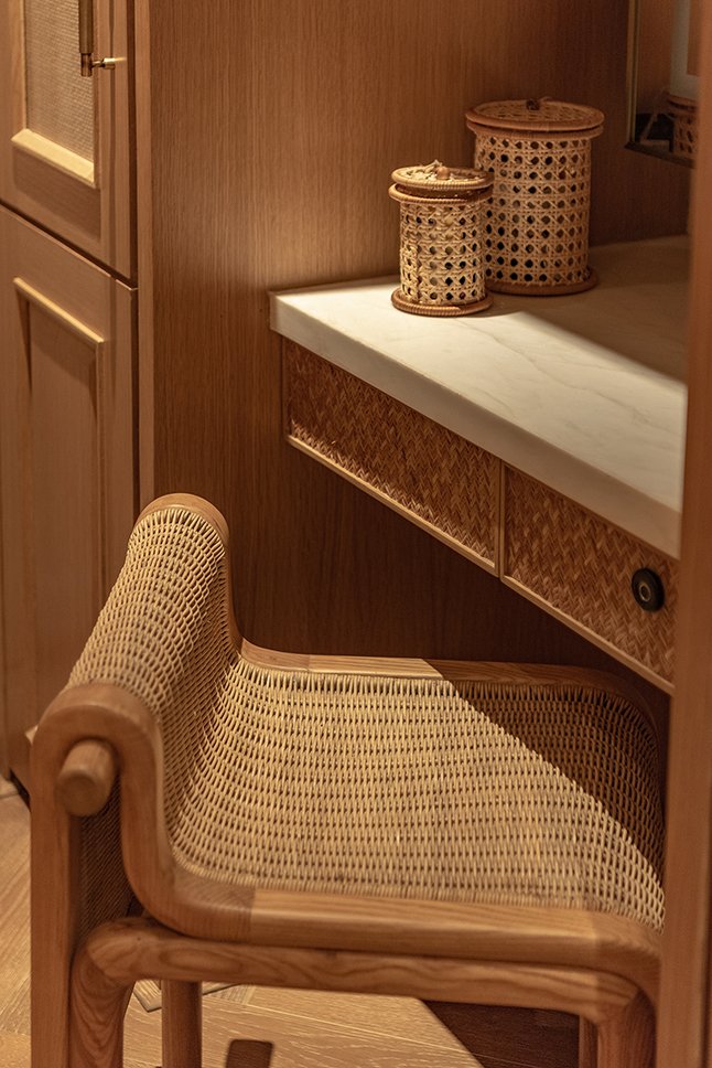 The vanity nook within the wardrobe, where a cane-backed chair rhymes with the cane-fronted drawers above